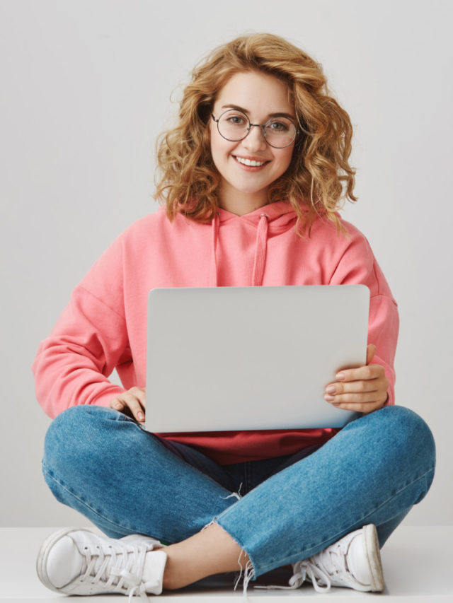cropped cute freelance girl using laptop sitting floor smiling