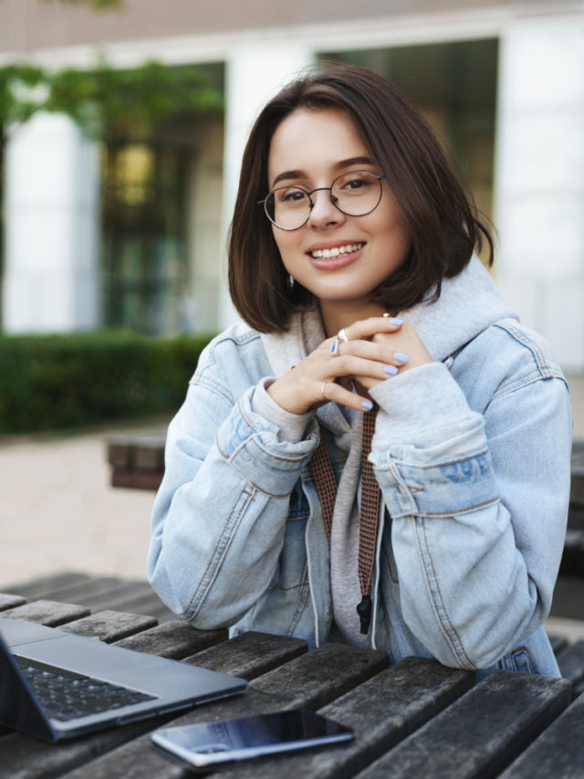 cropped freelance people education concept cheerful young attractive girl sitting alone park bench university working remote with laptop mobile phone look away with pleased smile